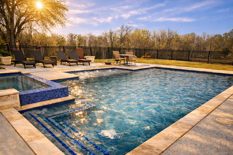 Custom inground swimming pool with raised spa and modern stone coping in East Texas backyard